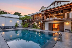 A modern house with a swimming pool, a covered outdoor area, and a staircase leading to a second floor. - NAYA (Saint-Martin)