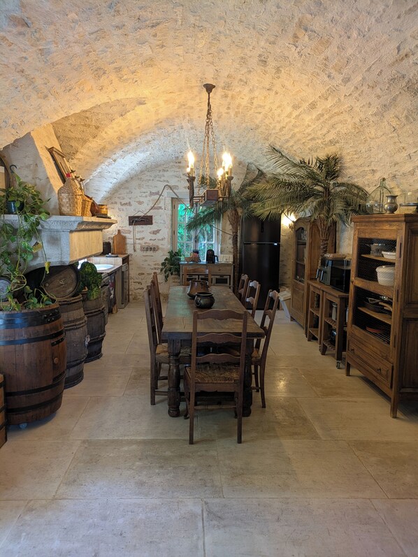 Comedor rústico con techo de piedra, muebles de madera y una araña.
