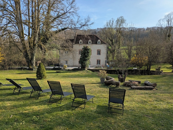 Un bĂątiment en pierre dotĂ© dâun jardin et dâun espace extĂ©rieur amĂ©nagĂ© pour sâasseoir.