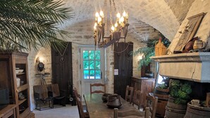 A rustic dining area with a long wooden table, chairs, a chandelier, and a stone ceiling. - LA TUILERIE DU CINEASTE An immersive bed and breakfast on the Côte D'Or cinema scene (Courlon)