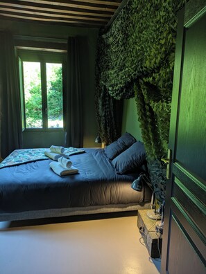 Une chambre Ă coucher avec un lit, une fenĂȘtre et un mur recouvert de feuillage.