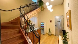 A staircase with a wrought iron railing, a refrigerator, a potted plant, and a wall-mounted light fixture.