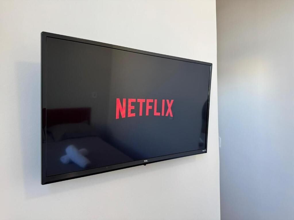 Een flatscreen-televisie bevestigd aan een muur, waarop het Netflix-logo wordt weergegeven.