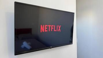 Een flatscreen-televisie bevestigd aan een muur, waarop het Netflix-logo wordt weergegeven.