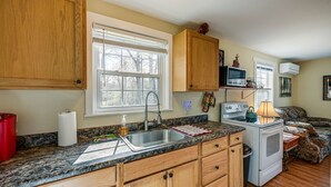 Una cocina con armarios de madera, encimera de granito, estufa, lavabo y ventana.