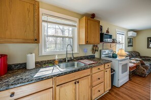 Una cocina con armarios de madera, encimera de granito, estufa, lavabo y ventana.