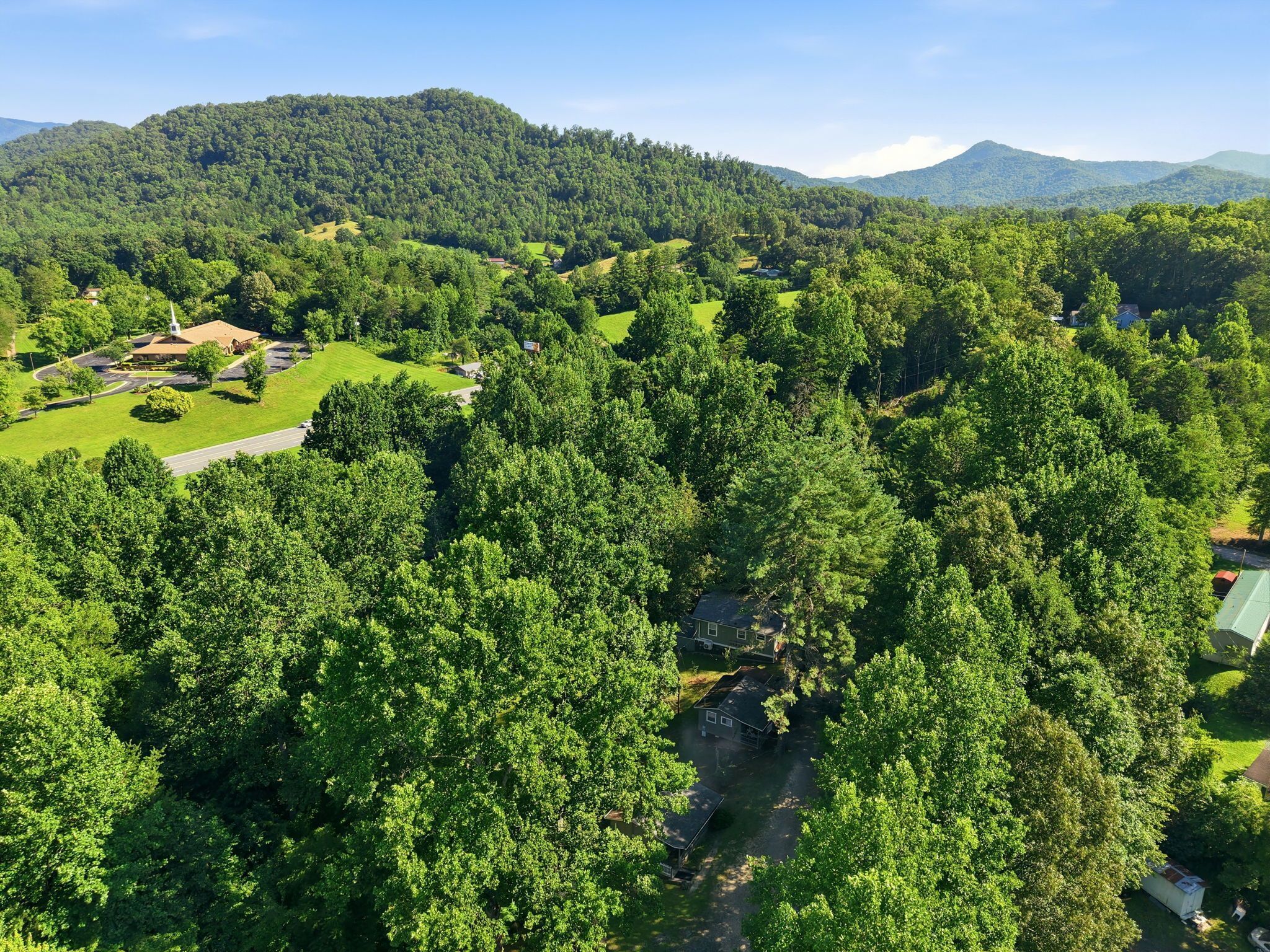 A lush green landscape with a church, a winding road, and scattered houses.