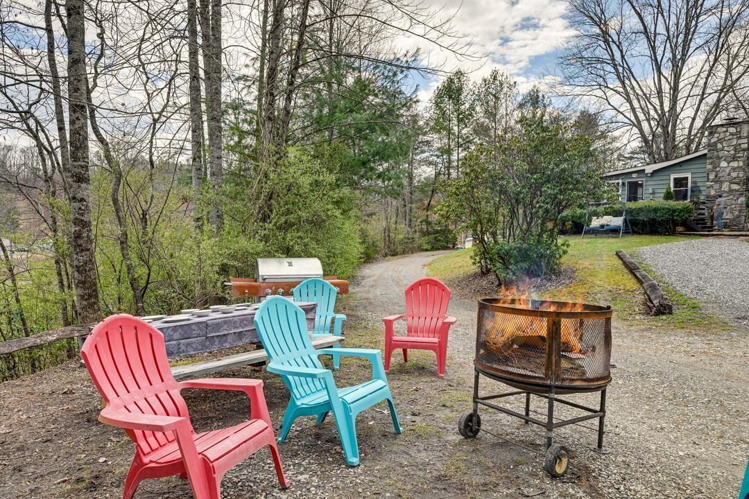 Um pátio de cascalho com cadeiras Adirondack, uma lareira e uma churrasqueira.