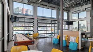 Un espacio interior amplio con ventanas grandes, mesa de billar y zonas de estar.