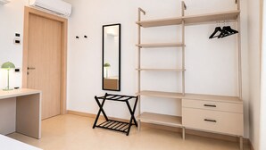 Un dormitorio con armario, espejo, escritorio y perchero.