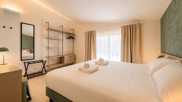 Una habitación de hotel con una cama grande, un armario, un escritorio y un espejo.
