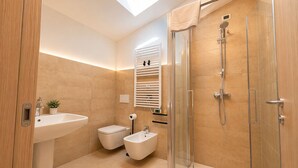 Un baño moderno con tragaluz, ducha, bidé y lavamanos.