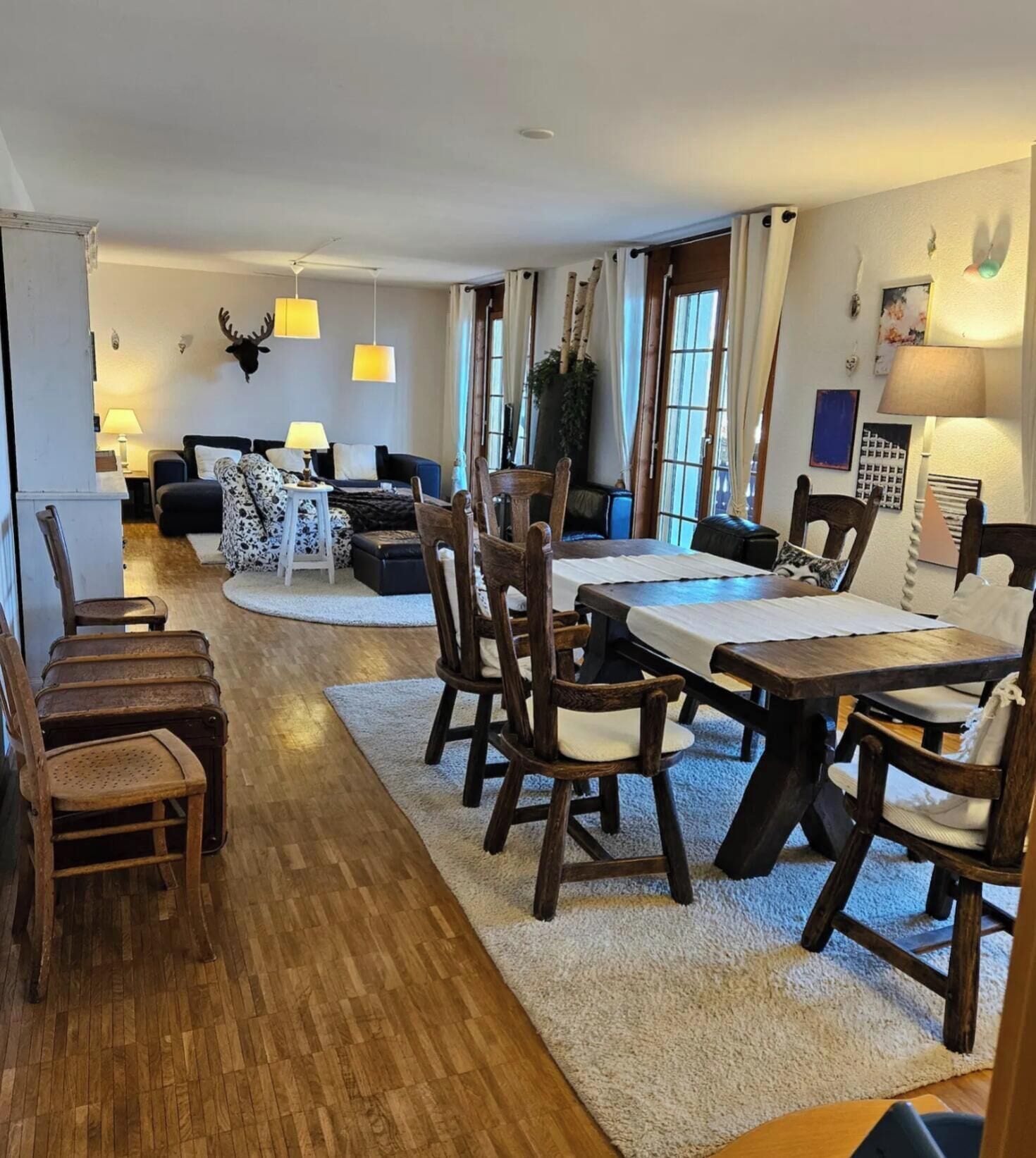 Ampla sala de estar com mesa de jantar, cadeiras de madeira, sofá e lareira.