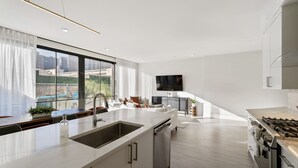 A modern kitchen with a large island, built-in oven, and a dining area with a view. - The Theodore New Orleans 3rd Floor Buyout (New Orleans)