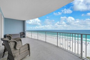 Ein Balkon mit Korbmöbeln, Blick auf den Strand und einen klaren Himmel.