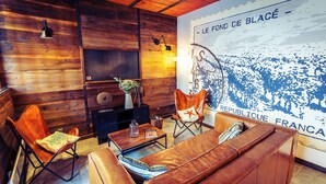 Una habitación acogedora con pared de madera, un sofá de cuero, una mesa de centro de madera y una silla.
