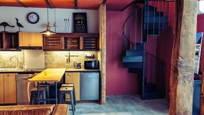 Una cocina moderna con vigas de madera, una escalera en espiral y una zona de comedor con sofá de cuero.