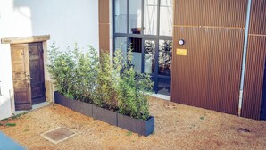 Un edificio con puerta de madera, una ventana y una jardinera con plantas.