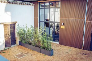 A building with a wooden door, a window, and a planter with plants.