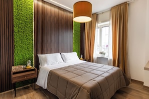 Una habitación de hotel moderna con una cama, una mesita de noche, una pared verde y una ventana con cortinas.