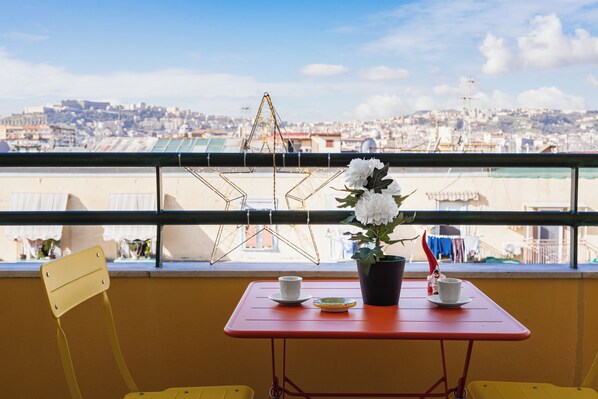 A balcony with a table, chairs, a potted plant, and a star decoration. - Seven Nap - Central Rooms (Naples)