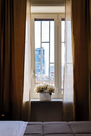 Een hotelkamer met een bed, een raam met gordijnen en uitzicht op gebouwen.
