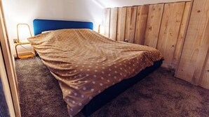 Une chambre à coucher avec un lit, une tête de lit en bois, une table de chevet et une lampe.