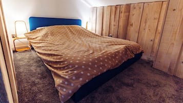 Une chambre à coucher avec un lit, une tête de lit en bois, une table de chevet et une lampe.
