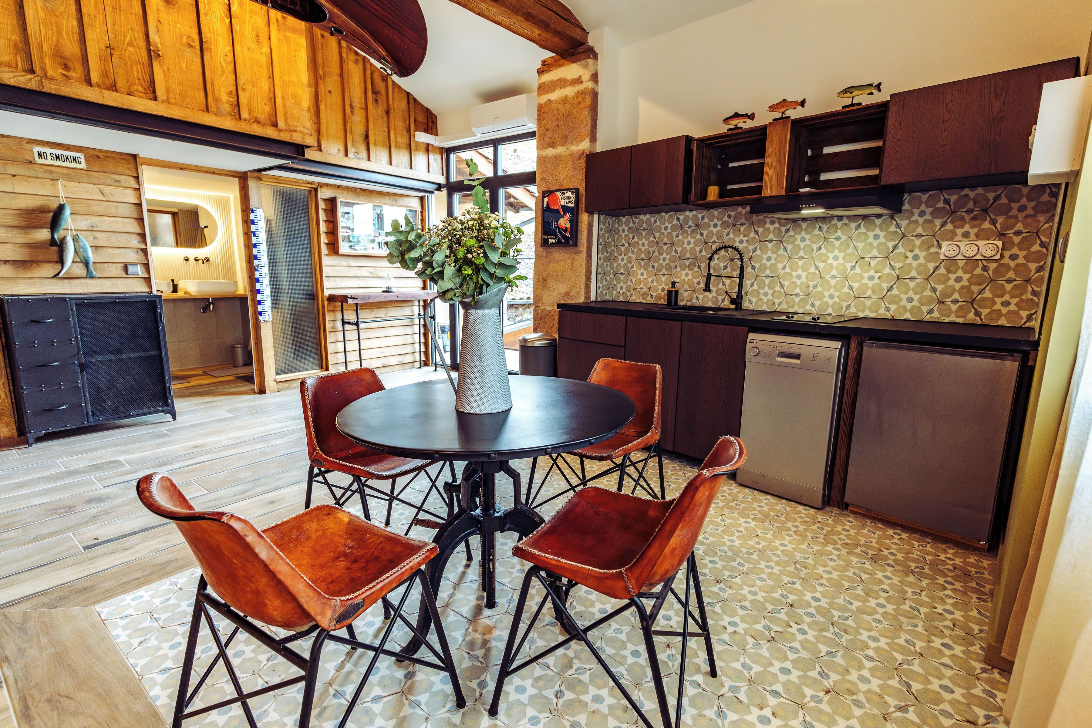 Une cuisine avec une table ronde, des chaises et un vase de fleurs.