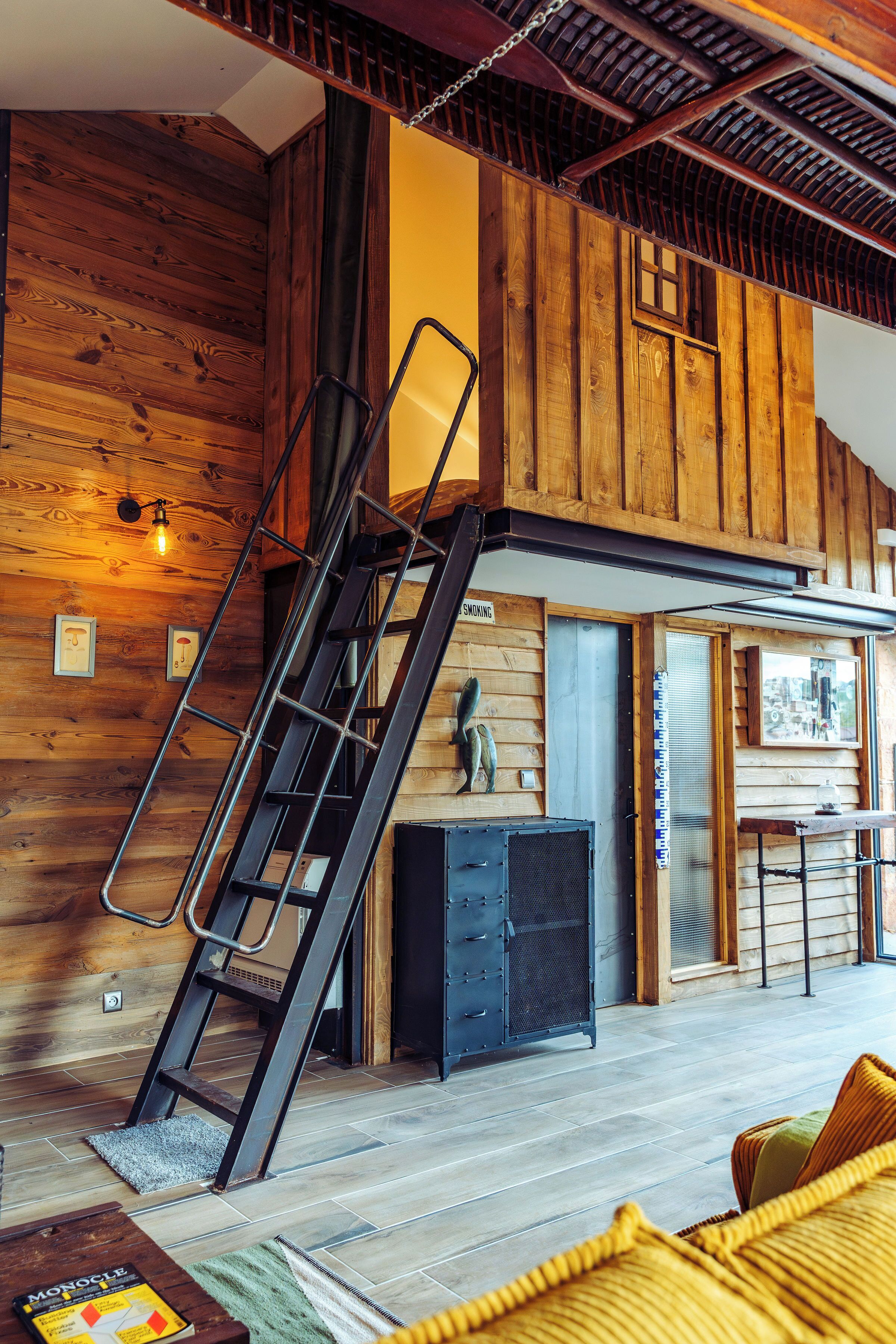 Een houten interieur met een trap, een open haard en een eethoek.