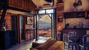 Un intérieur chaleureux avec un plancher en bois, un canapé, un coin repas et une cuisine dotée d’un mur recouvert de carreaux.