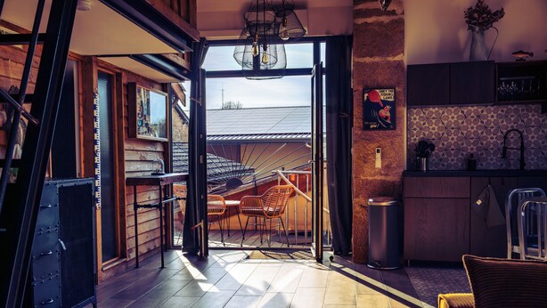 Un espace de vie à aire ouverte comprenant un escalier menant à un niveau supérieur, un coin cuisine et un coin repas avec des chaises.