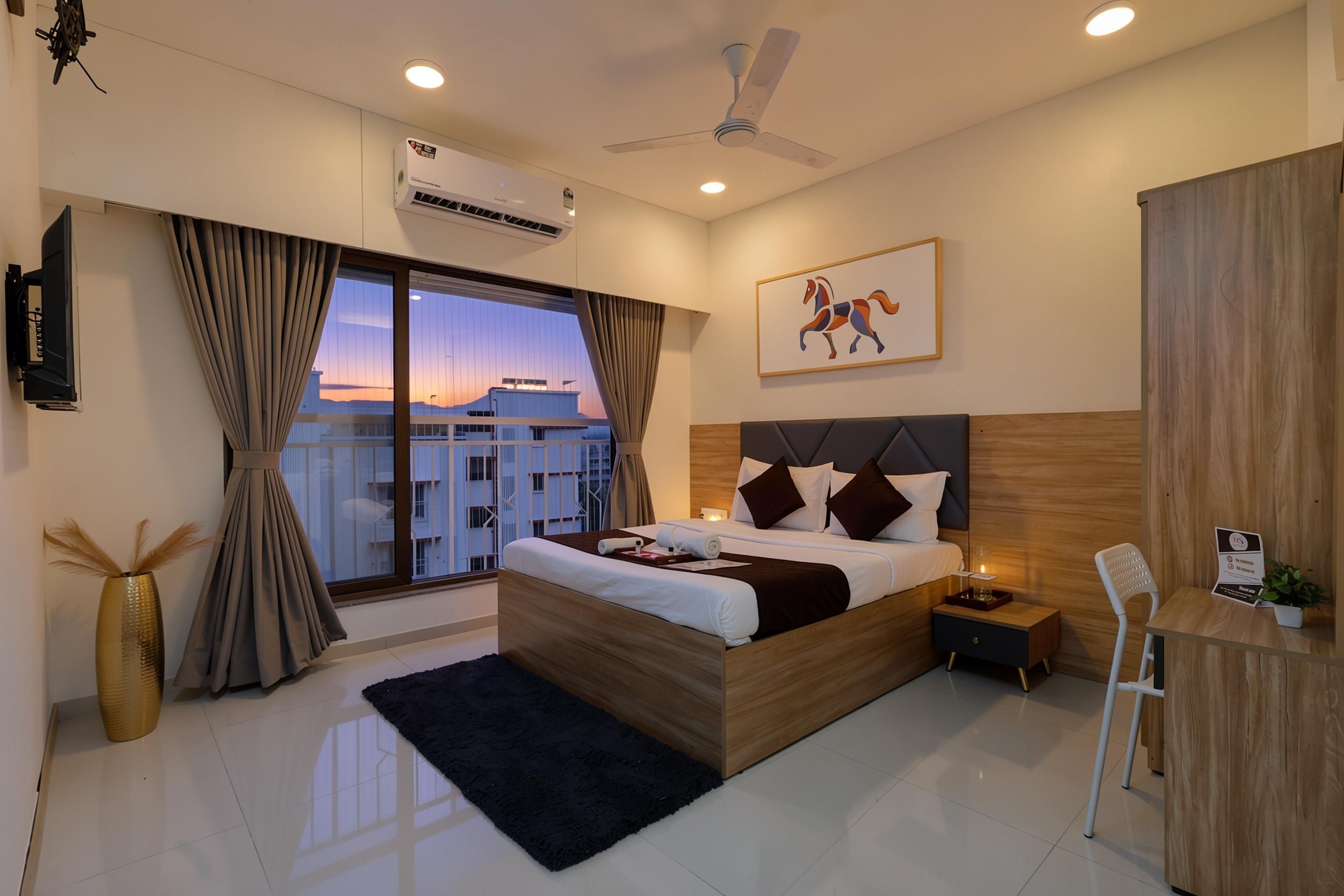 Habitación de hotel moderna con una cama grande, un escritorio, una silla, un televisor y vistas a la ciudad.