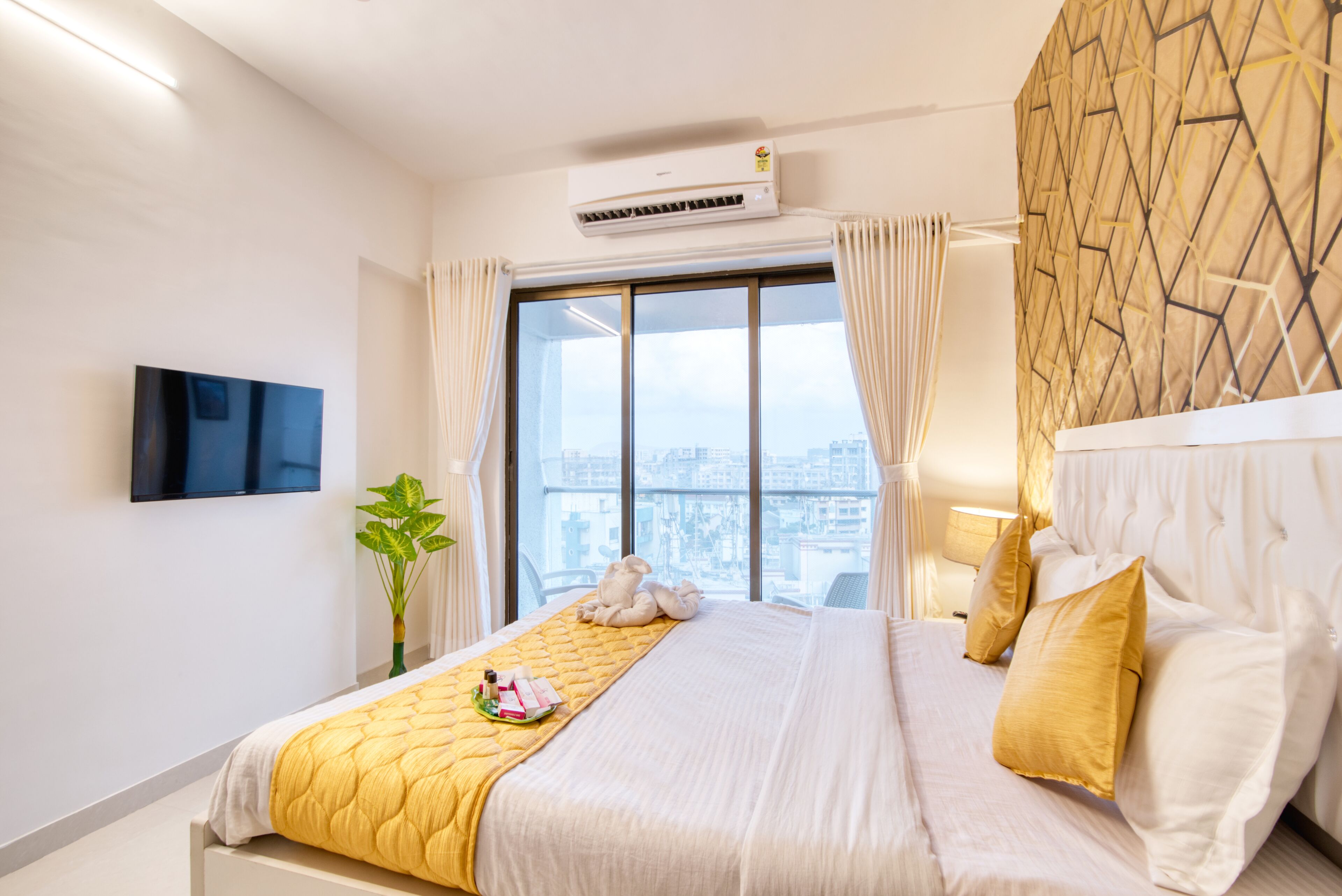 Une chambre d’hôtel équipée d’un lit, d’un téléviseur à écran plat, d’un climatiseur, d’une fenêtre avec des rideaux et offrant une vue sur la ville.