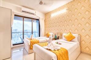 Una habitación de hotel con un ventanal grande, una cama, una mesita de noche y un papel tapiz estampado.