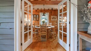 Un comedor de madera con una mesa, sillas, un ventilador de techo y una ventana con cortinas.