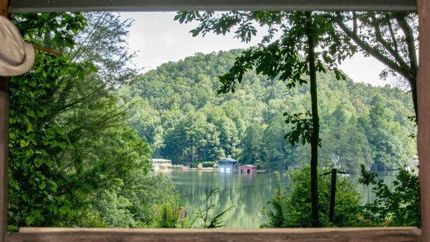 Vista desde una terraza de madera sobre un lago con edificios en la orilla opuesta.