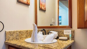 Una encimera de granito con un lavabo, un perchero y un espejo.