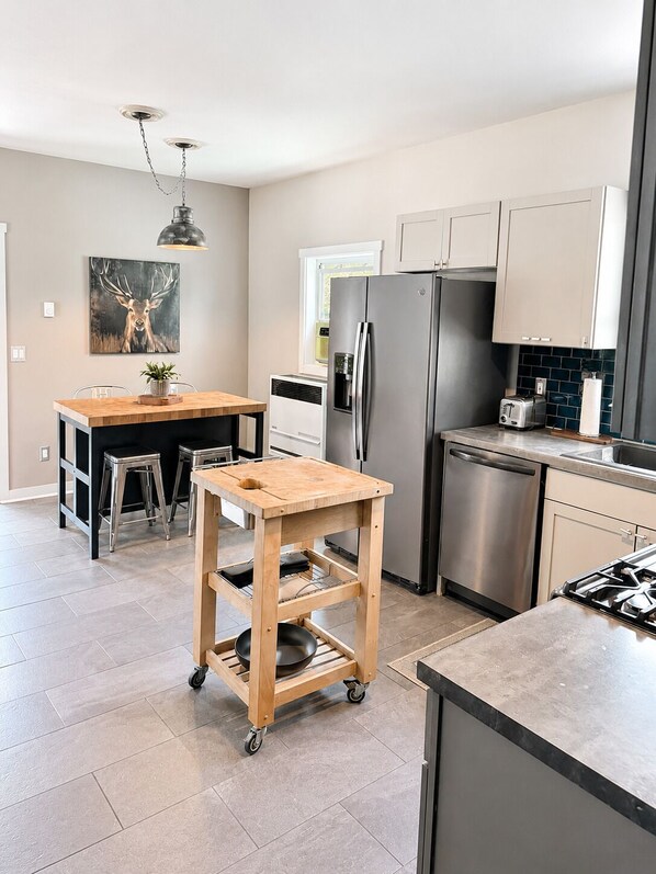 A modern kitchen with a central island, stainless steel appliances, and a dining area with stools.