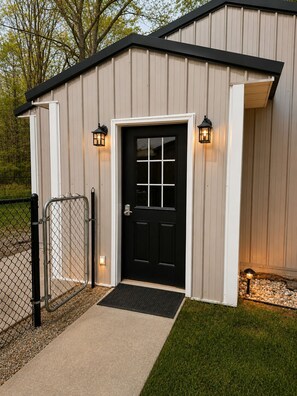 A building with a black door, white trim, and two wall-mounted lanterns.