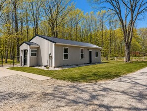 A single-story building with a metal roof, a gravel driveway, and a fenced property.