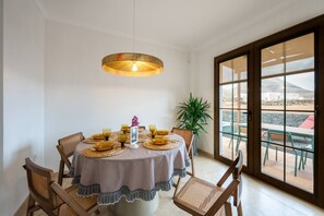 Ein Essbereich mit einem runden Tisch, Stühlen, einer Hängelampe und Blick durch eine Glastür.