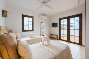 Ein Hotelzimmer mit zwei Betten, einem Deckenventilator, einem Fernseher und einem Balkon mit Blick.