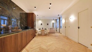 A modern kitchen with a herringbone floor pattern, wooden cabinetry, and a dining area with a round table and chairs. - AN AUTHENTIC PARISIAN LIVING AT BLVD SAINT GERMAIN (Paris)