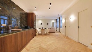 Eine moderne Küche mit Fischgrätparkett, Holzschränken und einem Essbereich mit rundem Tisch und Stühlen.