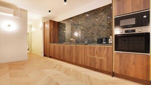 A modern kitchen with wooden cabinetry, a marble backsplash, and built-in appliances including a Bosch oven and microwave. - AN AUTHENTIC PARISIAN LIVING AT BLVD SAINT GERMAIN (Paris)