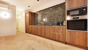 Eine moderne Küche mit Holzschränken, einer Marmor-Spritzschutzleiste und eingebauten Geräten, darunter ein Bosch-Backofen und eine Mikrowelle.