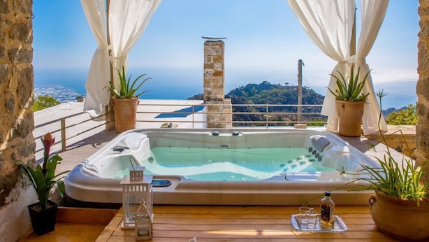 A hot tub with a view of the sea, surrounded by stone walls and potted plants. - Vacation home  by Interhome (Anatoli)