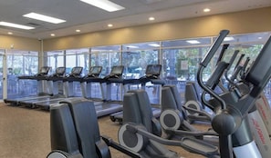 Un gimnasio con cintas de correr, elípticas y bicicletas estáticas.