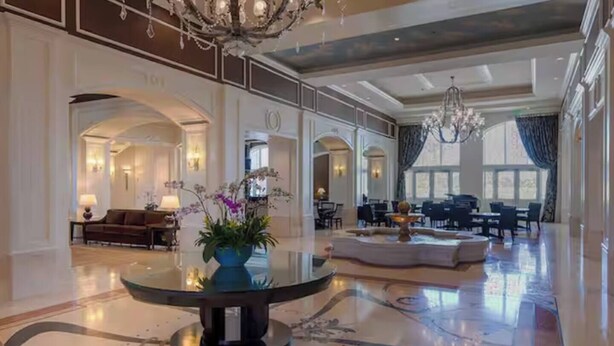 Eine geräumige Lobby mit einem runden Tisch, einer Sitzecke und einer Chandelier.
